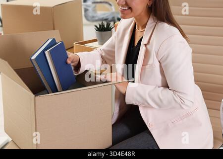 Beweglicher Tag. Frau, die im Büro Bücher in Pappkarton legt, Nahaufnahme Stockfoto