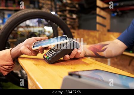 Junger Mann, der mit dem Smartphone über das kontaktlose Terminal bezahlt Stockfoto