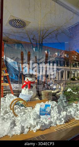 Ludwigsburg, Deutschland - 2. März 2025. Schaufenster mit einem Schneemann in schwarzem Hut und rotem Schal, Holzschlitten, Schlittschuhen und Skiern umgeben von künstlichen s Stockfoto