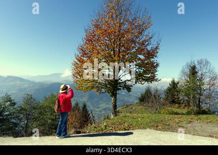 Reisende bewundern die Herbstberge unter Blue SK Ein Wanderer, von hinten gesehen, steht auf einem Bergüberblick mit Blick auf das weitläufige vall Stockfoto