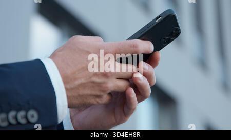 Nahaufnahme männlicher Hände, die Handy in der Stadt halten unerkennbarer Geschäftsmann chatten mit Smartphone-Gerät unbekannter Geschäftsmann mit Handy Stockfoto