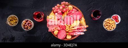 Italienisches Antipasti-Panorama. Wurstplatte mit Käse und anderen Snacks, mit Wein, Oliven usw., Flachbanner über dem Kopf Stockfoto