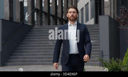 Erfolgreicher kaukasischer reifer Geschäftsmann männlich, der in der Stadt spazieren geht und das Büro verlässt. Geschäftsmann Manager mittleren Alters gehen nach draußen in die Nähe Stockfoto