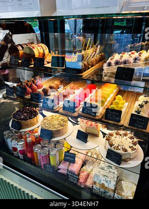 Kiew, Ukraine - 10. November 2025: Verschiedene Desserts und Gebäck stehen hinter Glas in einem gut beleuchteten Café. Stockfoto