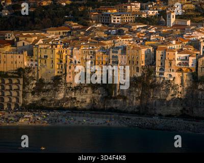 Aus der Vogelperspektive der sonnenverwöhnten Gebäude auf dramatischen Klippen treffen auf das azurblaue Meer, ein lebendiger Farbteppich und Textur, Tropea, Kalabrien, Italien. Stockfoto