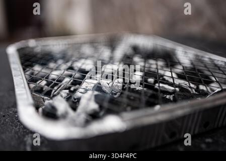 Ein Einweg-Grill mit den Kohlen, die zum Kochen bereit sind. Stockfoto