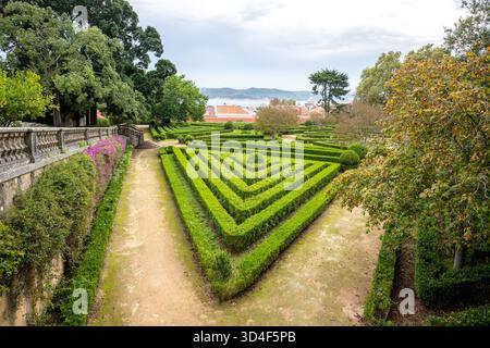 Formeller Dreieck-Heckengarten neben einer Steinterrasse mit violetten Blumen in Belem, Lissabon, Portugal. Stockfoto
