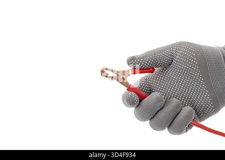 Eine Hand mit Handschuhen hält den roten Krokodilklemmendraht vor weißem Hintergrund und zeigt das Werkzeug, das für elektrische Verbindungen verwendet wird. Das Bild hebt den Griff hervor Stockfoto