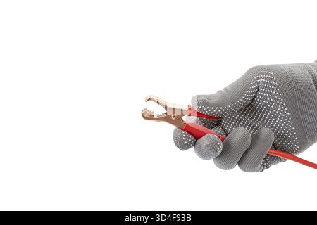 Eine Hand mit Handschuhen hält geöffnete Krokodilklemme mit rotem Kabel, isoliert auf weißem Hintergrund. Das Bild hebt die Funktionen und Sicherheitsfunktionen des Werkzeugs hervor Stockfoto