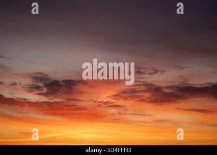 Lebendiger Himmel mit einem atemberaubenden Verlauf aus Rot, Orangen und Gelb mit dramatischen Wolken während eines farbenfrohen Sonnenuntergangs, der die natürliche Schönheit und die Atmosphäre der Dämmerung veranschaulicht Stockfoto