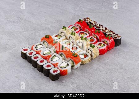 Essen, abwechslungsreiches kalifornisches Sushi-Sortiment mit Thunfisch-Maki-Lachs-Avocado-Rollen mit Sesamkruste und rotem Tobiko-Brötchen mit Inside-out-Sauce garniert mit Witz Stockfoto