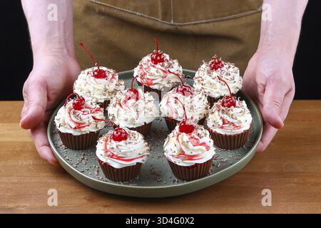Essen, Schokoladen-Cupcakes mit Schlagsahne, Maraschino-Kirschen und Schokoladenspäne auf grünem Teller Stockfoto