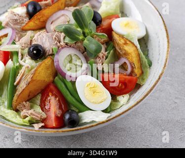 Essen, Salat mit Thunfisch in Dosen, Salat Nicoise, auf grauem Hintergrund für ein Menü auf der Essensseite Stockfoto