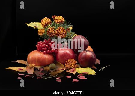 Stillleben im Herbst mit Äpfeln, Granatapfel, Kürbis und Ringelblumen auf schwarzem Hintergrund Stockfoto