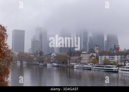 Frankfurt Skyline im Nebel am Mainufer 10.11.25, Frankfurt: Symbolfoto, Illustrationsbild, Symbolbild, Illustrationsfoto, Alltagsszene die Skyline von Frankfurt am Main an einem nebligen Herbstmorgen. Dichte Wolken und Nebel verhüllen die oberen Etagen der Hochhäuser im Bankenviertel, während die historische Altstadt mit Eiserner Steg, Schiffe und Mainufer im Vordergrund sichtbar bleiben. Das Bild zeigt den Kontrast zwischen moderner Architektur und historischer Stadtansicht in einer ruhigen, melancholischen Atmosphäre. Frankfurt am Main Hessen Deutschland *** Frankfurter Skyline im Nebel auf t Stockfoto