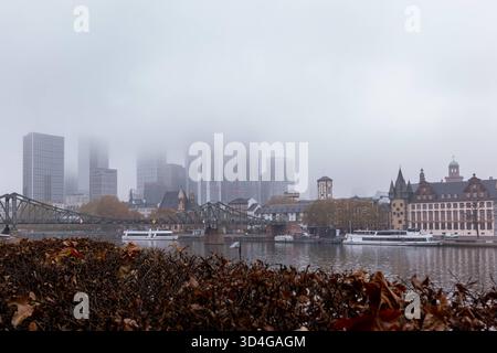 Frankfurt Skyline im Nebel am Mainufer 10.11.25, Frankfurt: Symbolfoto, Illustrationsbild, Symbolbild, Illustrationsfoto, Alltagsszene die Skyline von Frankfurt am Main an einem nebligen Herbstmorgen. Dichte Wolken und Nebel verhüllen die oberen Etagen der Hochhäuser im Bankenviertel, während die historische Altstadt mit Eiserner Steg, Schiffe und Mainufer im Vordergrund sichtbar bleiben. Das Bild zeigt den Kontrast zwischen moderner Architektur und historischer Stadtansicht in einer ruhigen, melancholischen Atmosphäre. Frankfurt am Main Hessen Deutschland *** Frankfurter Skyline im Nebel auf t Stockfoto