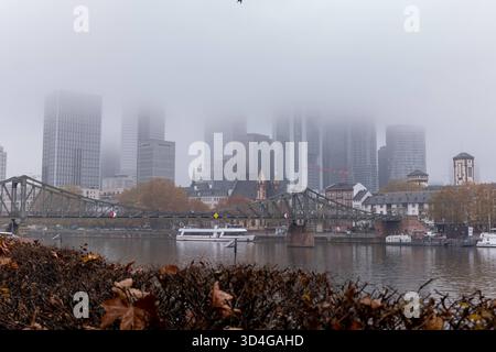 Frankfurt Skyline im Nebel am Mainufer 10.11.25, Frankfurt: Symbolfoto, Illustrationsbild, Symbolbild, Illustrationsfoto, Alltagsszene die Skyline von Frankfurt am Main an einem nebligen Herbstmorgen. Dichte Wolken und Nebel verhüllen die oberen Etagen der Hochhäuser im Bankenviertel, während die historische Altstadt mit Eiserner Steg, Schiffe und Mainufer im Vordergrund sichtbar bleiben. Das Bild zeigt den Kontrast zwischen moderner Architektur und historischer Stadtansicht in einer ruhigen, melancholischen Atmosphäre. Frankfurt am Main Hessen Deutschland *** Frankfurter Skyline im Nebel auf t Stockfoto