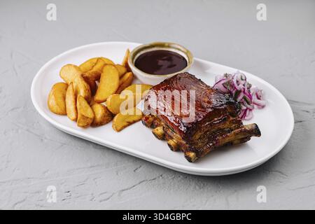 Essen, köstliche Platte mit glasierten Schweinerippchen mit Kartoffelscheiben, bbq-Sauce und Slaw auf einem weißen Teller Stockfoto