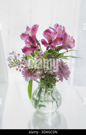 Essen, Vase mit rosa Frühlingsblumen. Weißer Hintergrund, selektiver Fokus Stockfoto