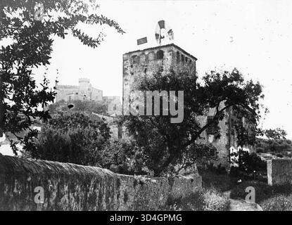 Diese Teilansicht von Cal Arnan zeigt einen quadratischen Turm und eine Windmühle, die von Antoni Gallardo i Garriga im Jahr 1918 aufgenommen wurden. Das Foto zeigt die ländliche Architektur der katalanischen Landschaft. Stockfoto