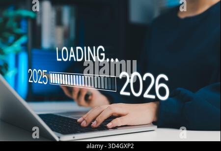 Neujahr-Übergangskonzept. Frau mit Laptop mit Ladebalken von 2025 bis 2026, symbolisiert Planung, Änderung, Zielsetzung, nächstes Jahr Stockfoto
