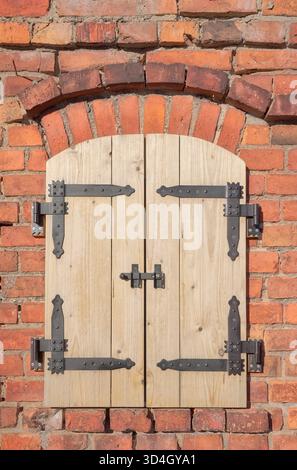 Alte Ziegelmauer mit neuen Holzläden. Stockfoto