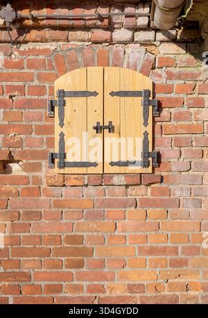 Alte Ziegelmauer mit neuen Holzläden. Stockfoto