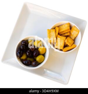 Schwarze und grüne Oliven. Knusprige Chips oder Cracker als Snack Stockfoto