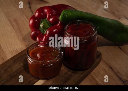 Frische rote und grüne Paprika mit hausgemachter Salsa und gerösteten Pfefferkonserven Stockfoto