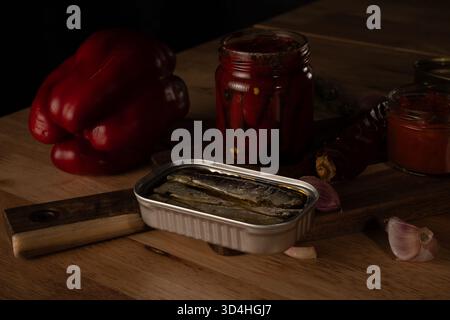 Dosenfisch, eingelegte Paprika und Gemüse schaffen ein rustikales Stillleben Stockfoto