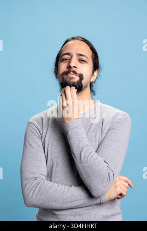 Ein Mann aus dem Nahen Osten, der vor der Kamera verwirrt und unsicher ist, besinnlich ist und über etwas nachdenkt. Unsicher neugieriger Kerl, der über neue Ideen nachdenkt, Introspektion. Stockfoto