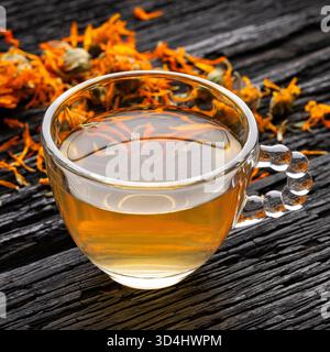 Calendula Kräuterinfusion serviert in einer klaren Glasschale auf einem rustikalen Hintergrund - Calendula officinalis Stockfoto