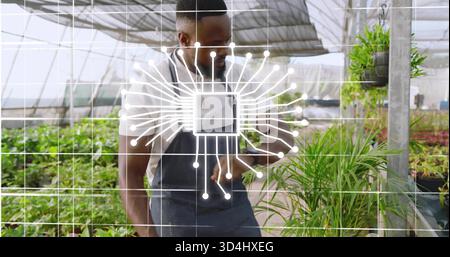 Gärtner in dunkler Schürze und weißem Hemd inspiziert Töpfe im Gewächshaus mit Mikrochip-Gitterüberlagerung Stockfoto