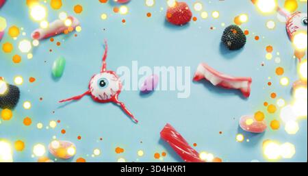 Mit Augapfelgummi mit 3 roten Lakritzsträngen, die auf einer blassblauen Matte sitzen, mit Vampirzähnen Stockfoto