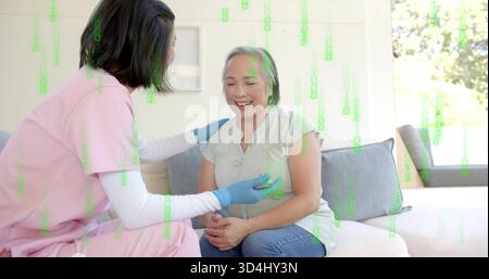 Lächelnde Seniorin, die den Impulssensor auf dem Sofa hat, pinkfarbene Scheuerschwester mit blauen Handschuhen, grüner Überzug Stockfoto