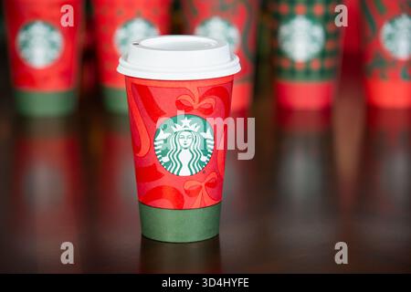 Dallas, Texas - 9. November 2025: Nahaufnahme des Starbucks Drinks im neuen festlichen Weihnachtsbecher 2025. Eine Reihe von Weihnachtsbechern im Hintergrund. Stockfoto