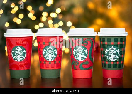 Dallas, Texas - 9. November 2025: Eine Reihe von Starbucks-Getränken in den neuen 2025 gestalteten festlichen Bechern. Weihnachtsbeleuchtung Hintergrund. Stockfoto