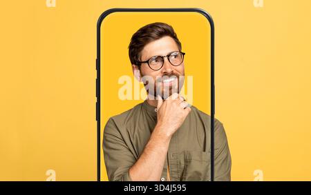 Ein nachdenklicher Mann posiert in einem modernen gelben Hintergrund mit einer künstlerischen Rahmenstruktur Stockfoto