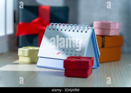 Ein Dezember-Schreibtischkalender, der Weihnachten und den zweiten Weihnachtsfeiertag hervorhebt, ist umgeben von farbenfrohen Geschenkboxen in verschiedenen Größen, die Weihnachtsverkäufe symbolisieren Stockfoto