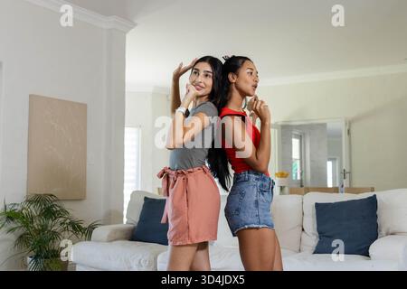 Verschiedene weibliche Freunde stehen im Wohnzimmer, mit Sofa, Pflanzen- und Leinwandkunst Stockfoto