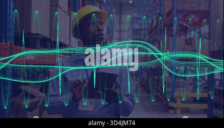 Tablette halten, Arbeiter im Depot tragen gelben Schutzhelm, ID-Emblem überprüft die Racks mit blauer Kurve Stockfoto