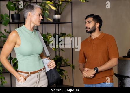 Im modernen, minimalistischen Showroom mit schwarzem Metallregal stehen verschiedene Kollegen Stockfoto