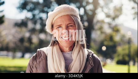 Kleidung, Porträt und Lächeln einer alten Frau im Park für Pause, Ruhestand oder Winter Wellness. Mode, Outfit und Style mit glücklicher Seniorin im Freien Stockfoto