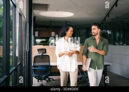 Verschiedene Kollegen, Frauen und Männer, diskutieren Online-Projekte und haben Spaß im Büro Stockfoto