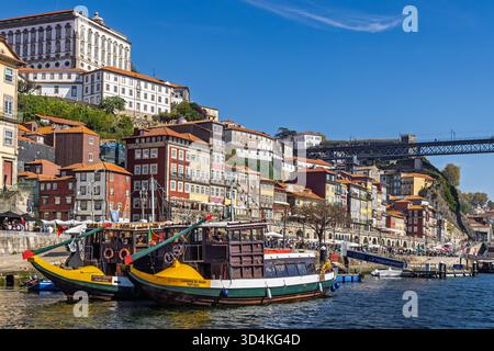 Ragelo-Boote, die an der Uferpromenade von Ribeira unter Reihenhäusern und der Brücke Dom Luís i, Porto, Portugal, ankern Stockfoto