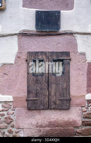 Rustikale geschlossene Holzfenstern an der Steinmauerfassade des alten Gebäudes, mittelalterlicher Architekturstil Stockfoto