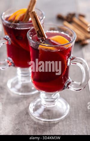 Glühwein mit Orangen- und Zimtstangen und Weihnachtsdekoration auf Holztisch Stockfoto