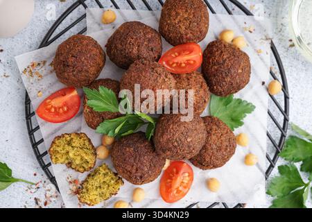 Stehen Sie mit köstlichen Falafelbällchen, Kichererbsen und Tomaten auf hellem Hintergrund, Nahaufnahme Stockfoto