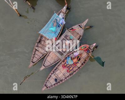 Dhaka, Bangladesch - 31. August 2024: Blick aus der Vogelperspektive auf traditionelle Holzboote, die mit bunten Stoffen geschmückt sind und sanft auf dem ruhigen, trüben Wasser ruhen Stockfoto