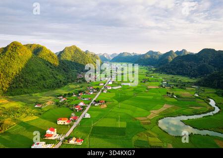Blick aus der Vogelperspektive auf das rustikale Dorf zwischen üppig grünen Reisfeldern im Vorort im Bac Son Valley, Vietnam Stockfoto